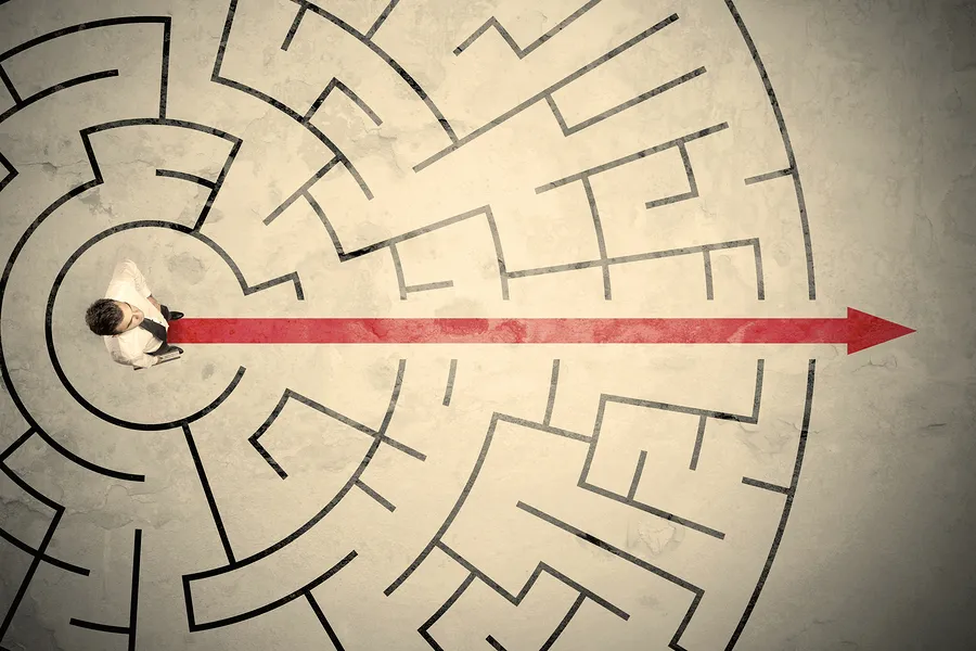 Concept image looking down on a man cutting directly through a maze
