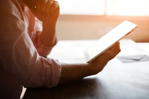 Closeup of a mans hands reading a tablet