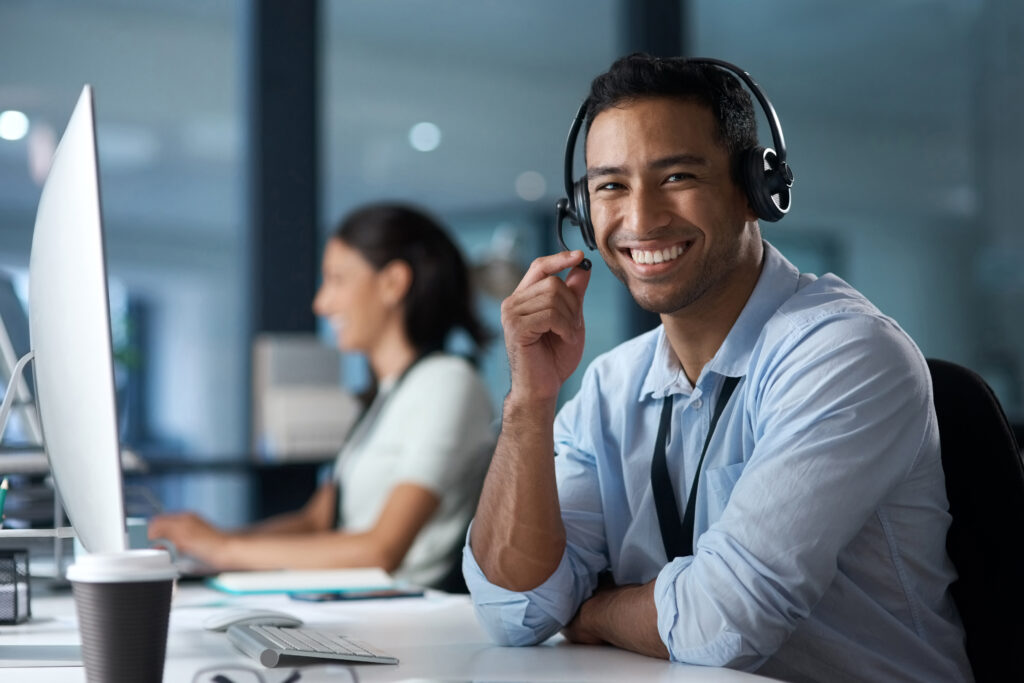 Portrait of a young man using a headset and computer in a modern office. Providing white label SEO services.