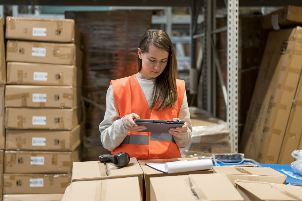 A woman with a tablet actively working in a warehouse environment, overseeing inventory and operations. Amazon FBA calculator Canada emphasizes the integration of technology and logistics expertise required for efficient management.