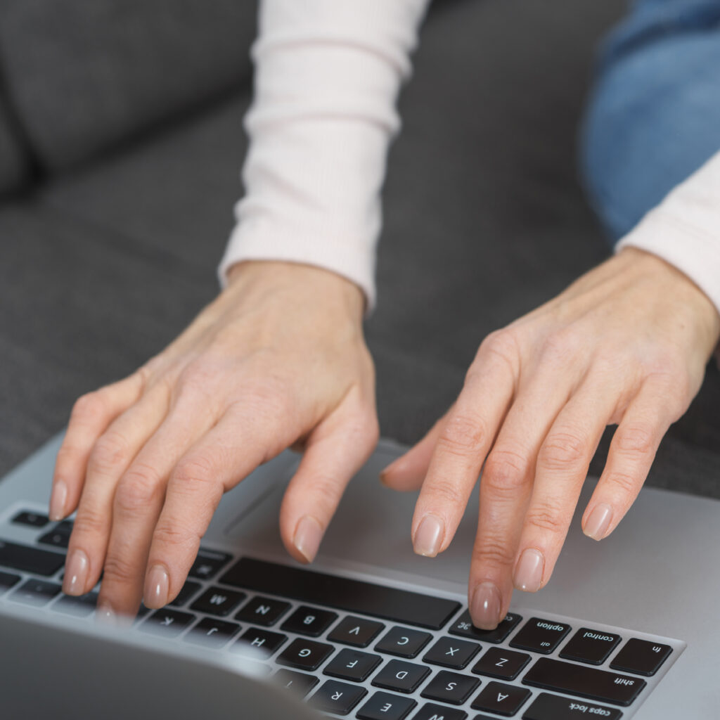 Close-up of a woman's hands typing on a laptop inputting data into a Google Ads cost calculator for an advertising budget analysis.