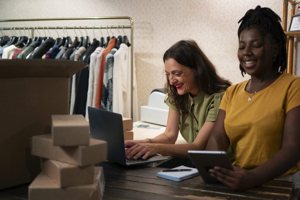 Two entrepreneurial women packaging clothing for their Amazon headline search ads to boost sales.