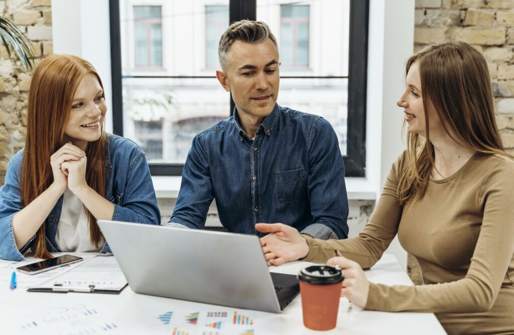 Three professionals huddle around a laptop, seemingly analyzing data that could answer the lingering question "is SEO still relevant" for their business strategies.