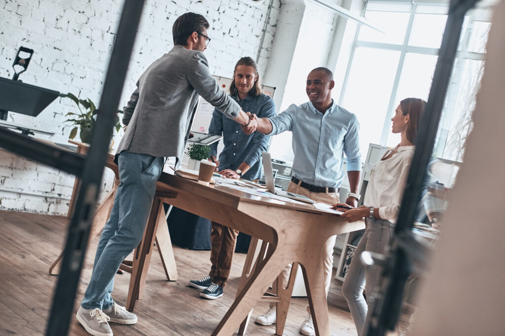 Modern professionals shaking hands during a business meeting, planning around the cost of Google sponsored ads.