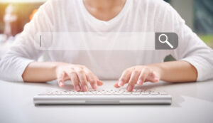 a white keyboard with a search bar in focus, illustrating the action of keyword searching. This visual emphasizes the importance of understanding how to look for keywords on a website for better online visibility and search engine performance.