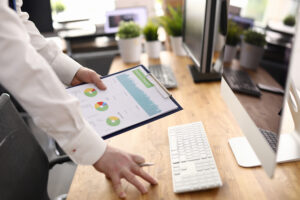 A close-up view of a businessperson holding a printed statistical report with various colorful pie and bar charts, ready for analysis. Keywords: "monitor organic results."