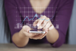 A focused image of a person holding a smartphone, overlaid with a line graph and bar charts, symbolizing "advantages of digital marketing" like real-time analytics and targeted outreach.