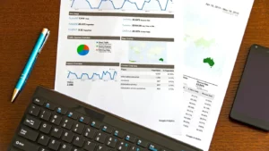 A printed analytics report with charts and performance metrics next to a keyboard and pen, representing data analysis for Google Ads landing page optimization.