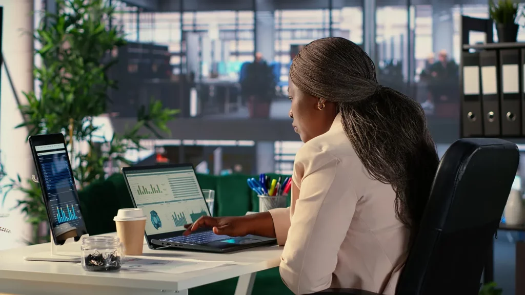 Google ads search terms report being reviewed by executive woman in an office sitting at a laptop on a desk 